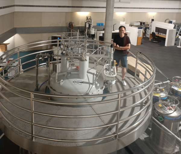 Ivanhoe Leung standing by a NMR machine