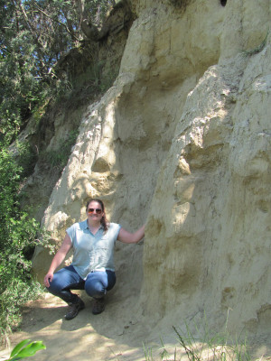 Dr Yates crouches next to a cut loess slope 