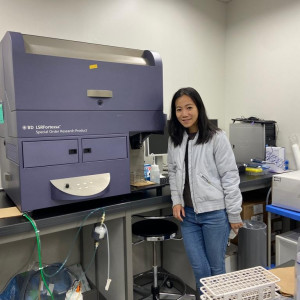 Dr Catherine Tsai stands next to a lab machine