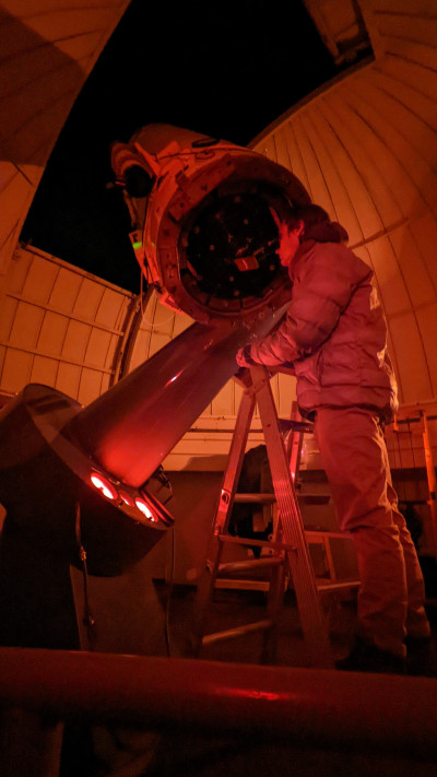 Dr Harper stands atop a stepladder to look into a viewfinder